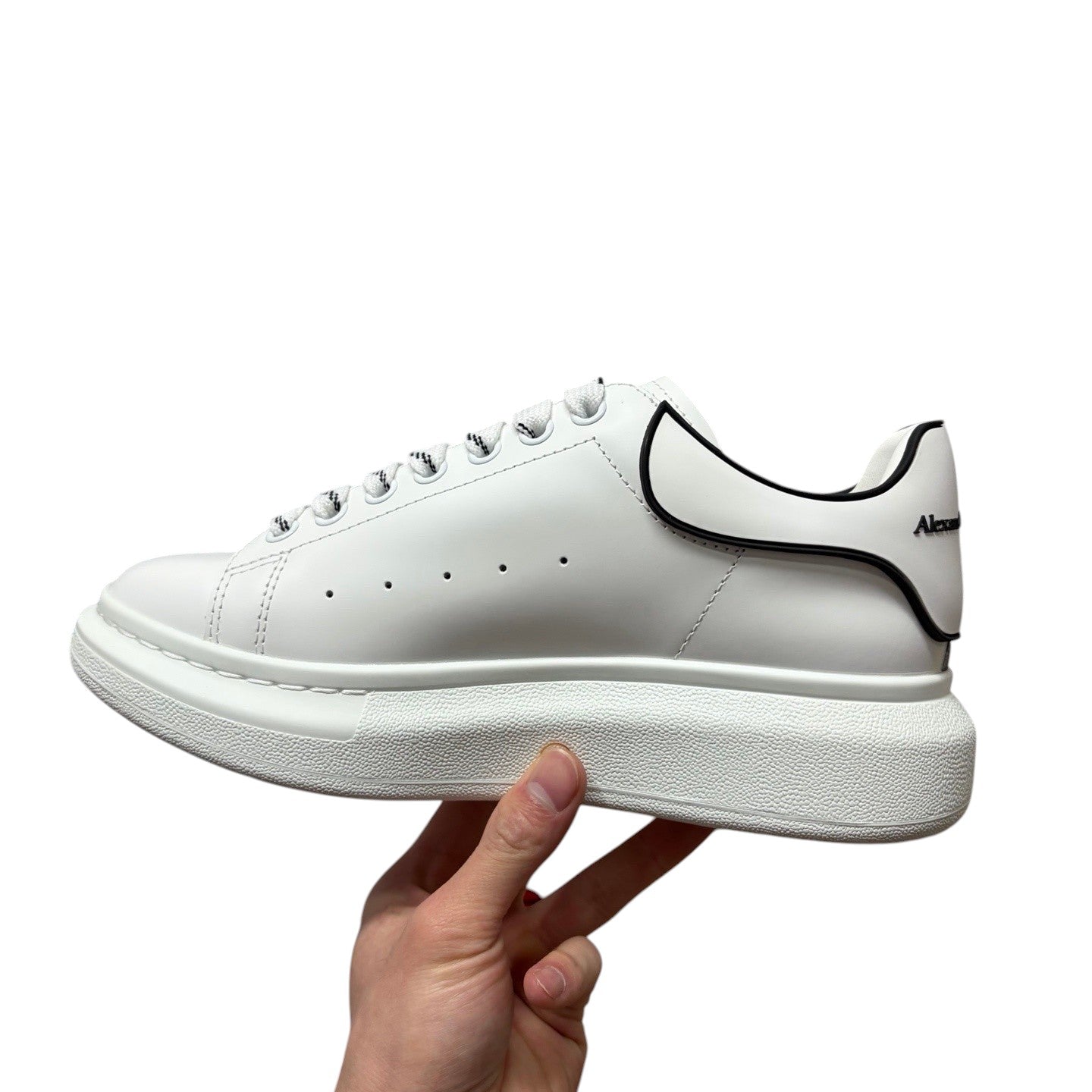 Luxury Chef Alexander McQueen white leather sneakers with black trim and chunky sole.