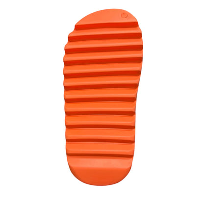 Luxury Chef orange Yeezy slide with a ridged sole, held by a hand.