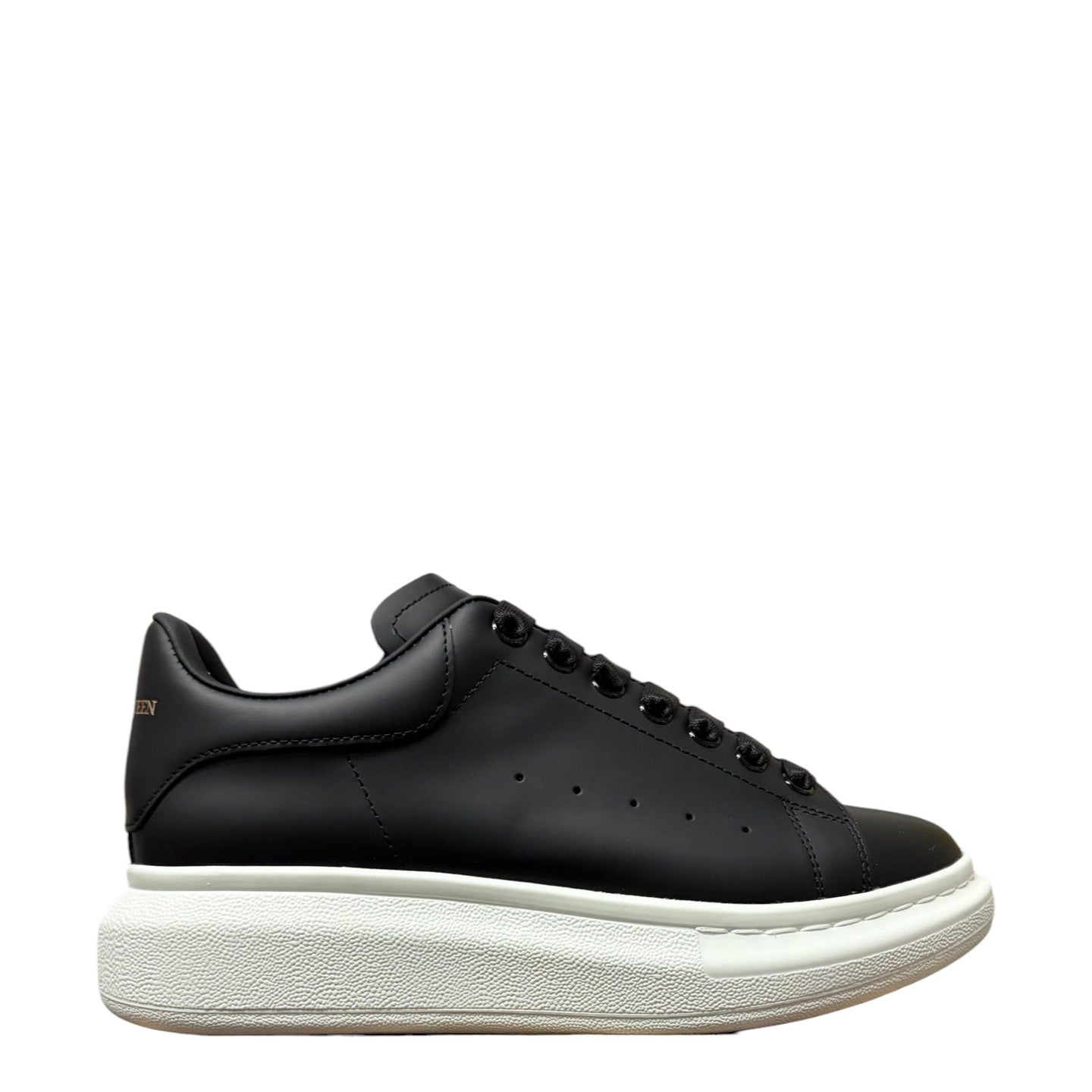 Luxury Chef Alexander McQueen black leather sneakers with white platform sole and signature heel tab.