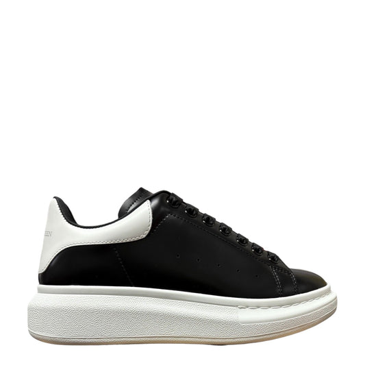 Luxury Chef Alexander McQueen black leather sneakers with white heel tab and chunky white sole.