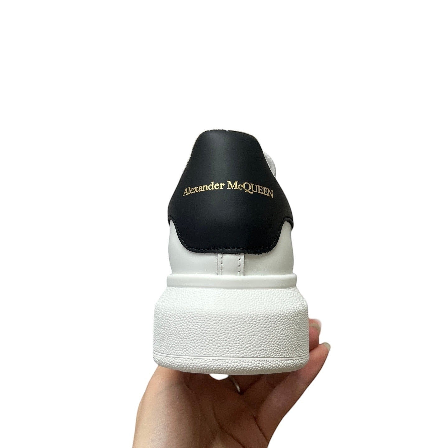 Luxury Chef Alexander McQueen white leather sneakers with black heel tab and gold logo.