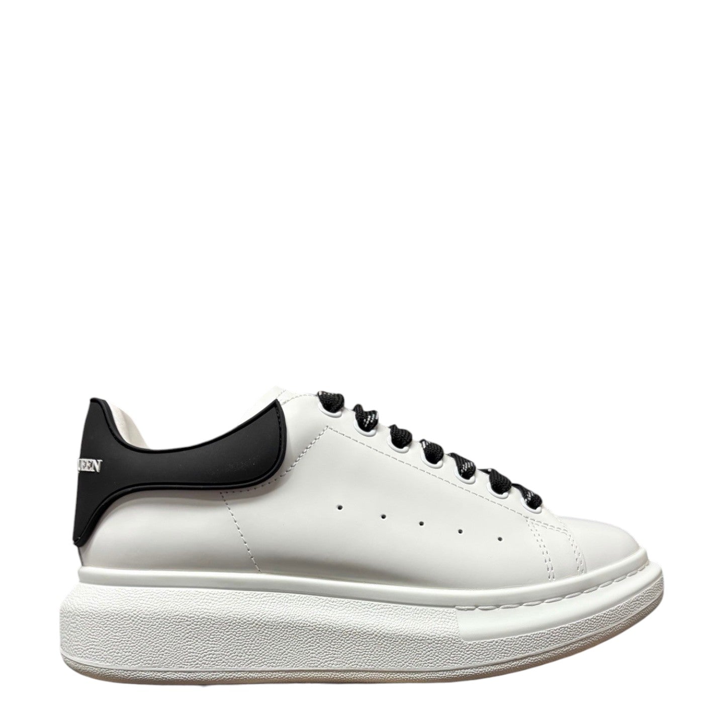 Luxury Chef Alexander McQueen white leather sneakers with black heel tab and black laces. Chunky white sole.