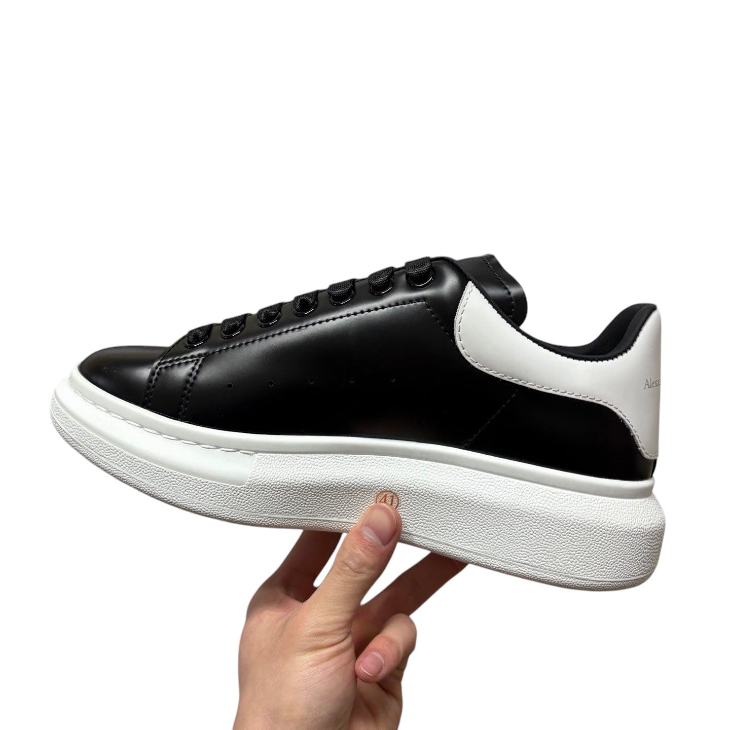 Luxury Chef black leather sneakers with white heel tab and thick white sole. Alexander McQueen branding.