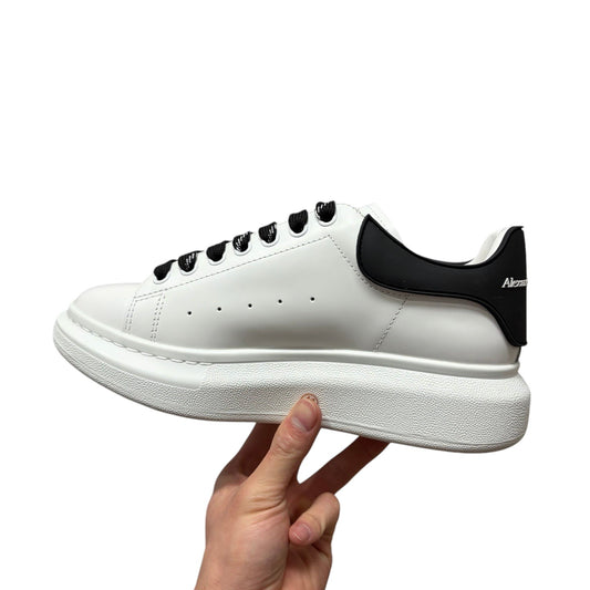 Luxury Chef Alexander McQueen white leather sneakers with black heel tab and laces, featuring a chunky sole.