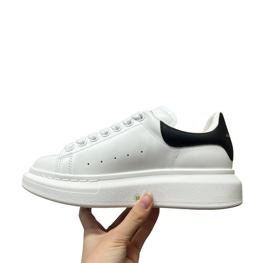 Luxury Chef Alexander McQueen white leather sneakers with black heel tab and chunky sole.