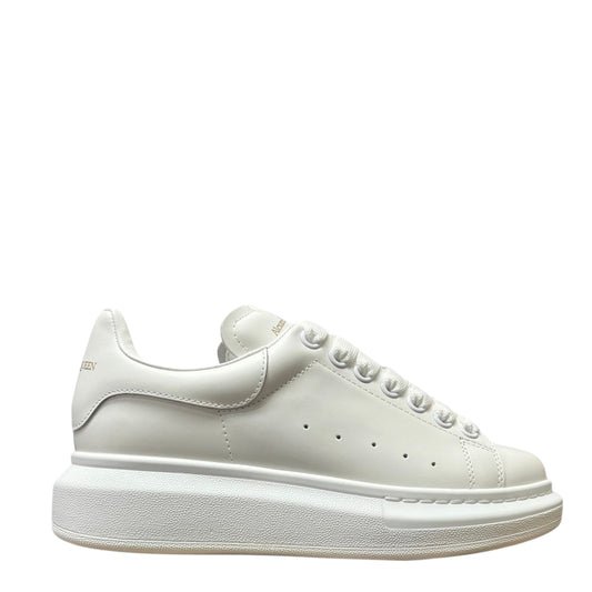 Luxury Chef Alexander McQueen white leather oversized sole sneakers with gold logo detail.