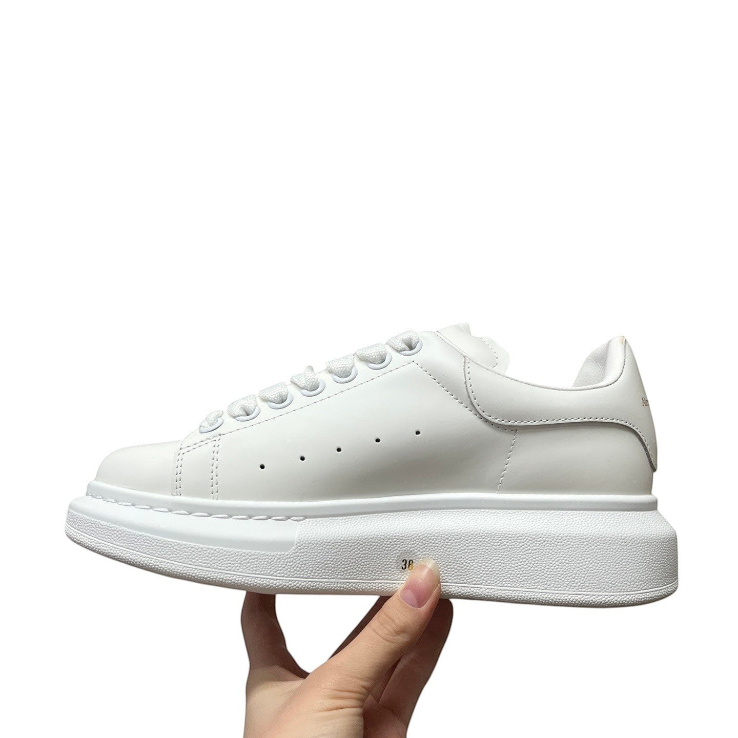 Luxury Chef Alexander McQueen white leather oversized sole sneakers with signature perforations and lace-up closure.
