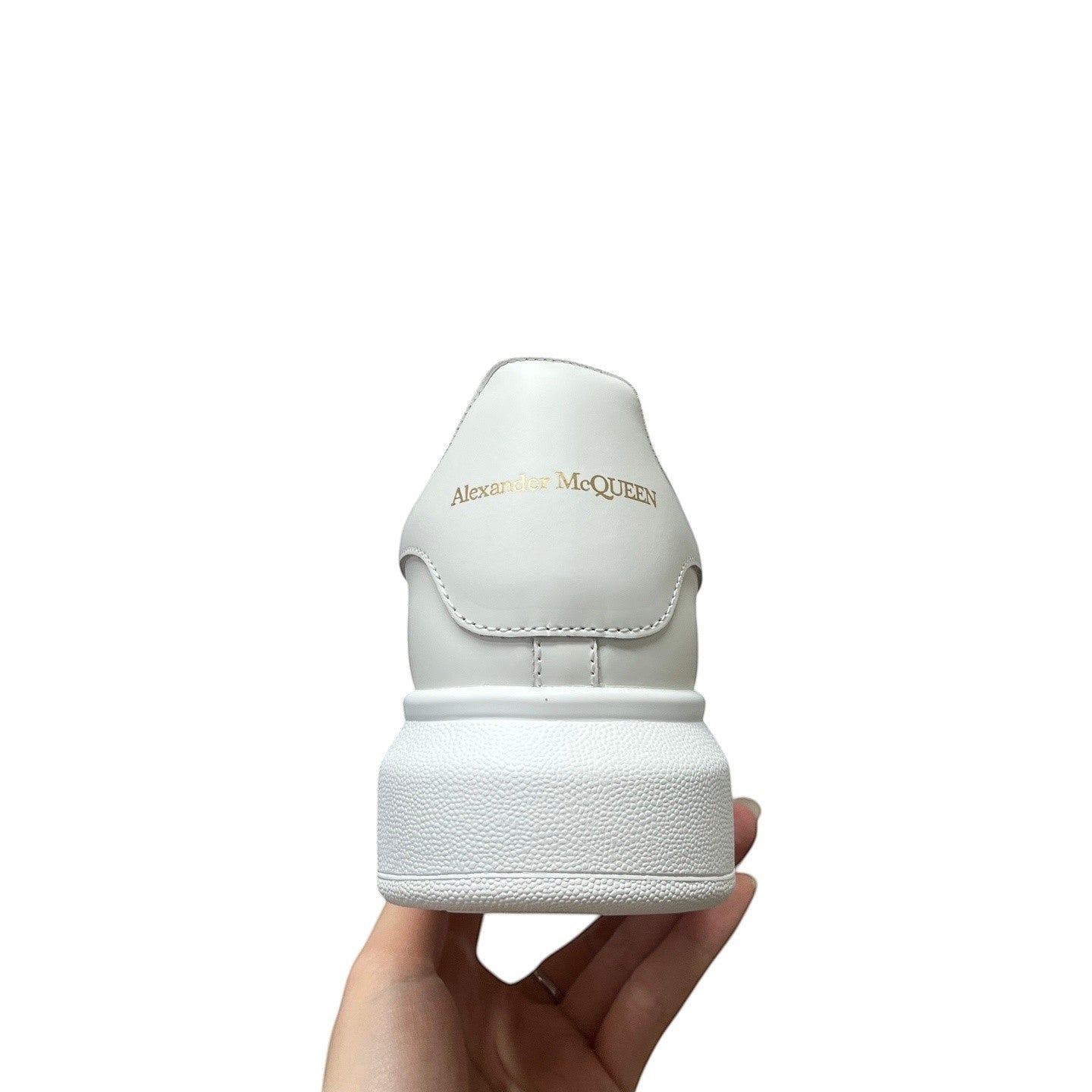 Luxury Chef white leather Alexander McQueen sneakers with gold logo detail and platform sole.