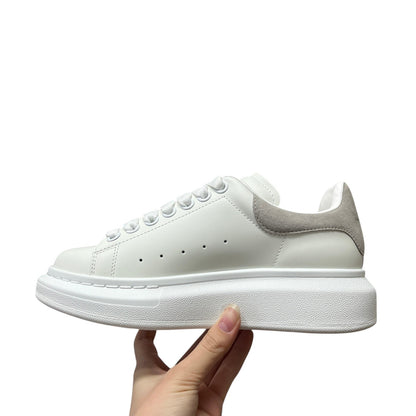 Luxury Chef Alexander McQueen white leather sneakers with grey suede heel detail and thick white sole.