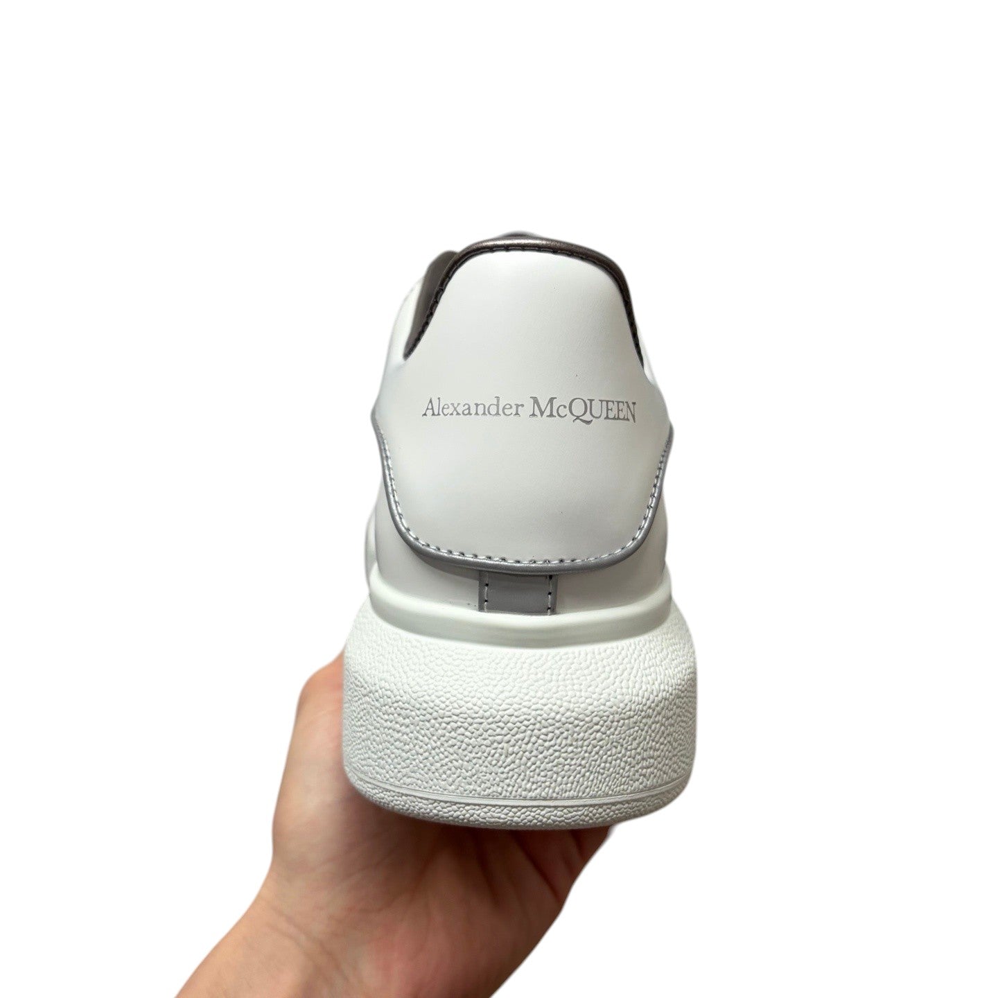Luxury Chef Alexander McQueen white leather sneakers with silver trim and chunky sole.