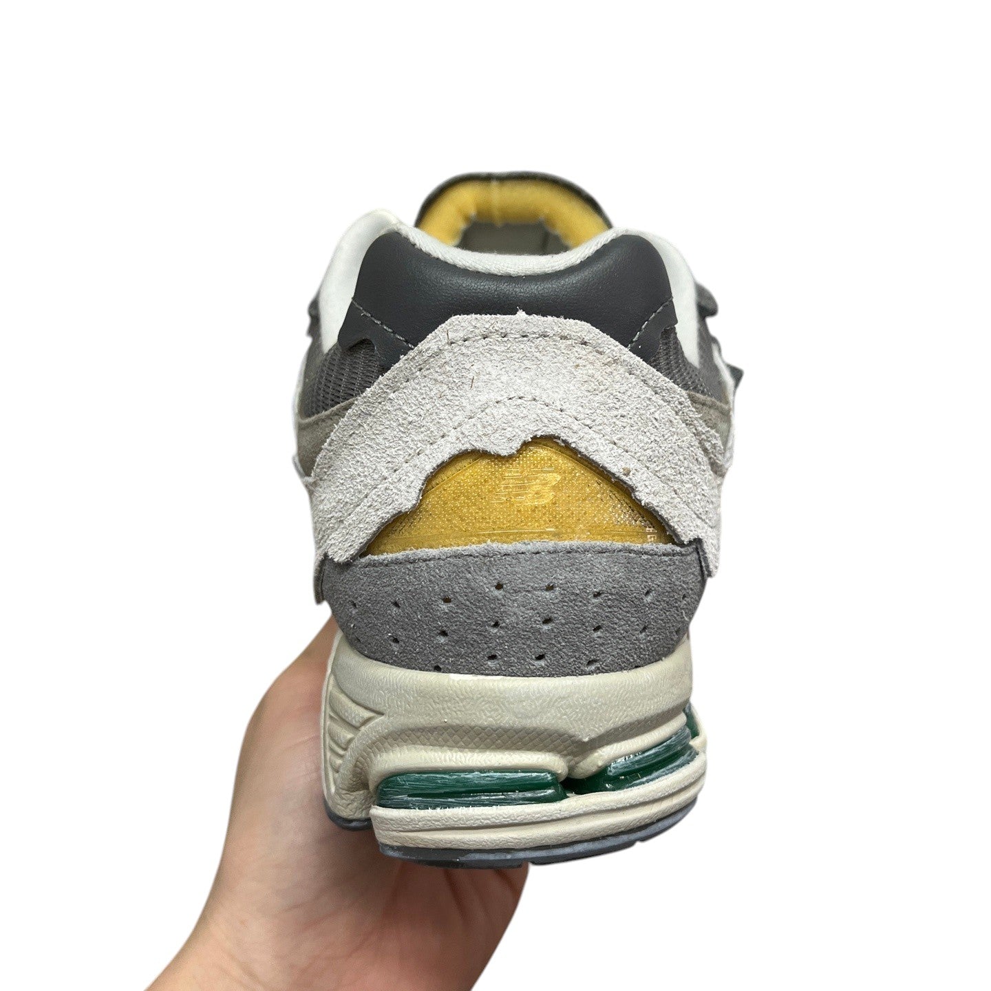 Luxury Chef New Balance 2002R grey suede and mesh sneakers with yellow accents and green sole details.
