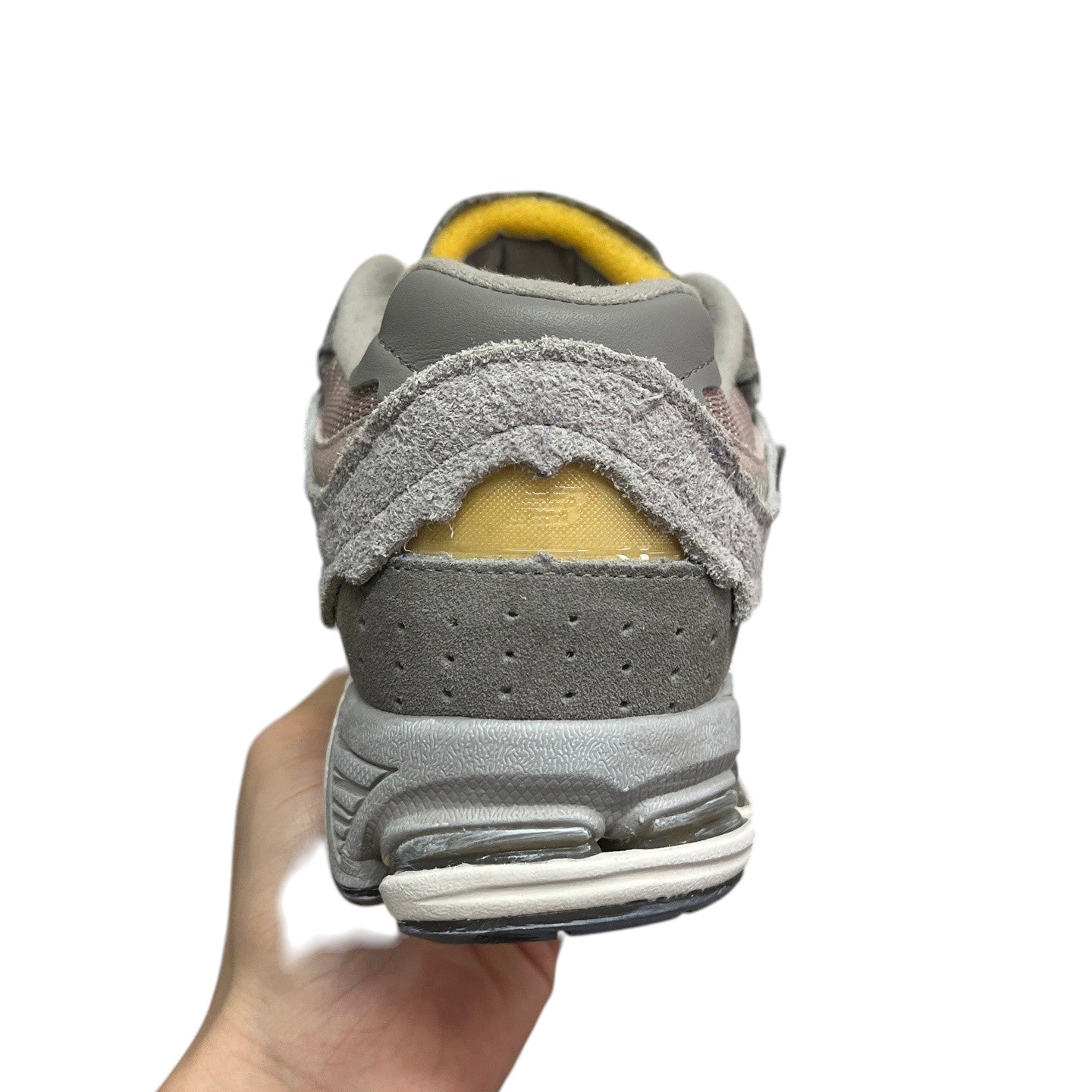 Luxury Chef NEW BALANCE 2002R grey suede sneakers with distressed detailing and yellow accents.