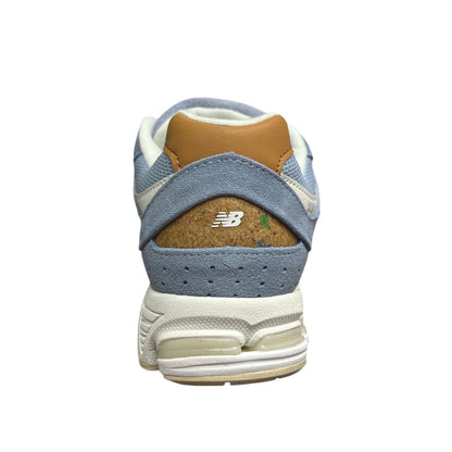 Luxury Chef New Balance 2002R light blue suede sneakers with tan heel accent and cork heel detail.