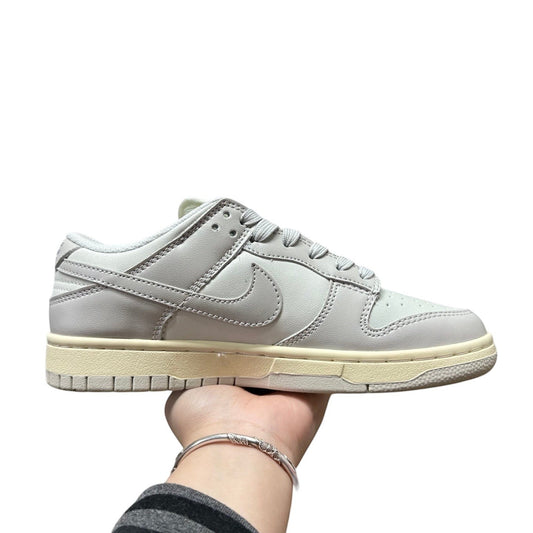 Luxury Chef Nike Dunk Low light grey leather sneakers with cream sole and white laces.