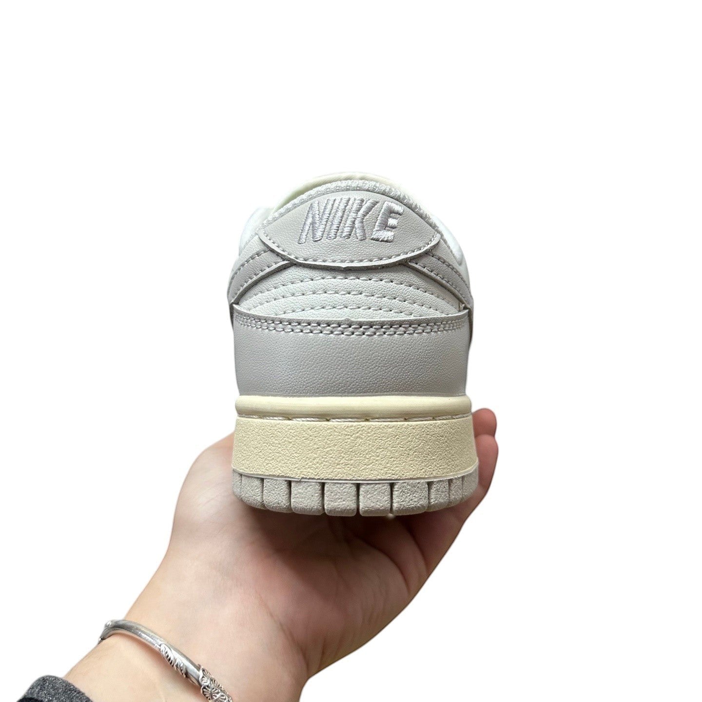 Luxury Chef Nike Dunk Low light grey leather sneakers with cream sole and Nike logo on heel.