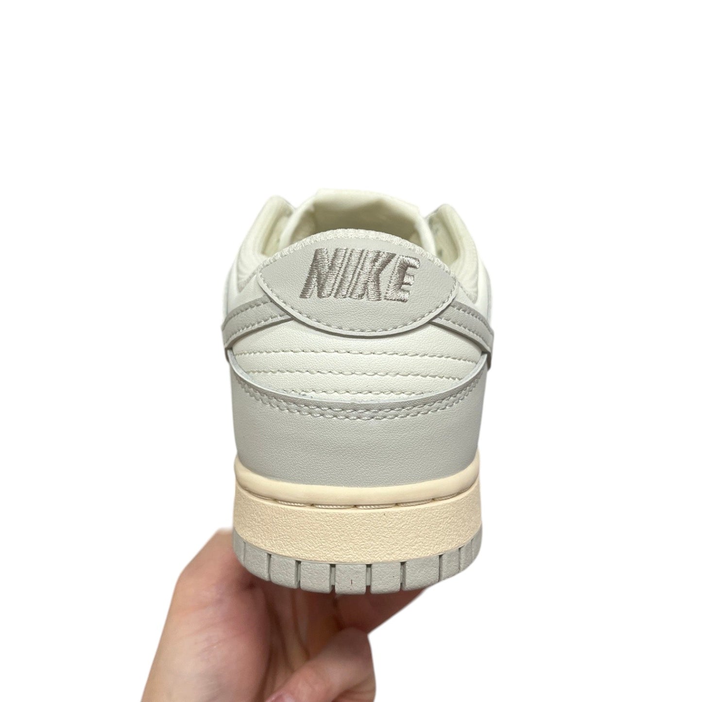 Luxury Chef Nike Dunk Low off-white and grey leather sneakers with embroidered Nike logo on heel.