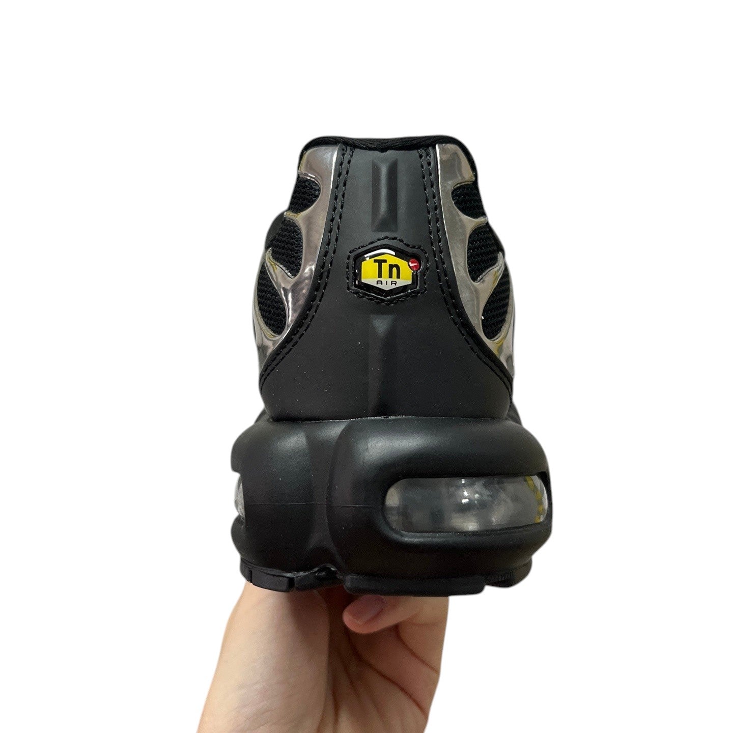 Luxury Chef Nike TN Air black sneakers with silver accents and visible air cushioning. Yellow Tn Air logo detail.
