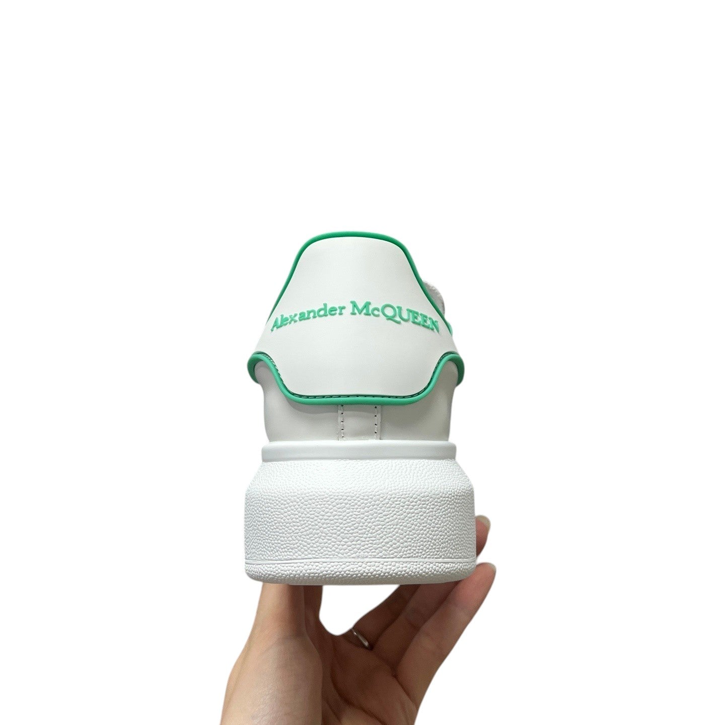 Luxury Chef white leather sneakers with green trim and Alexander McQueen logo on heel.