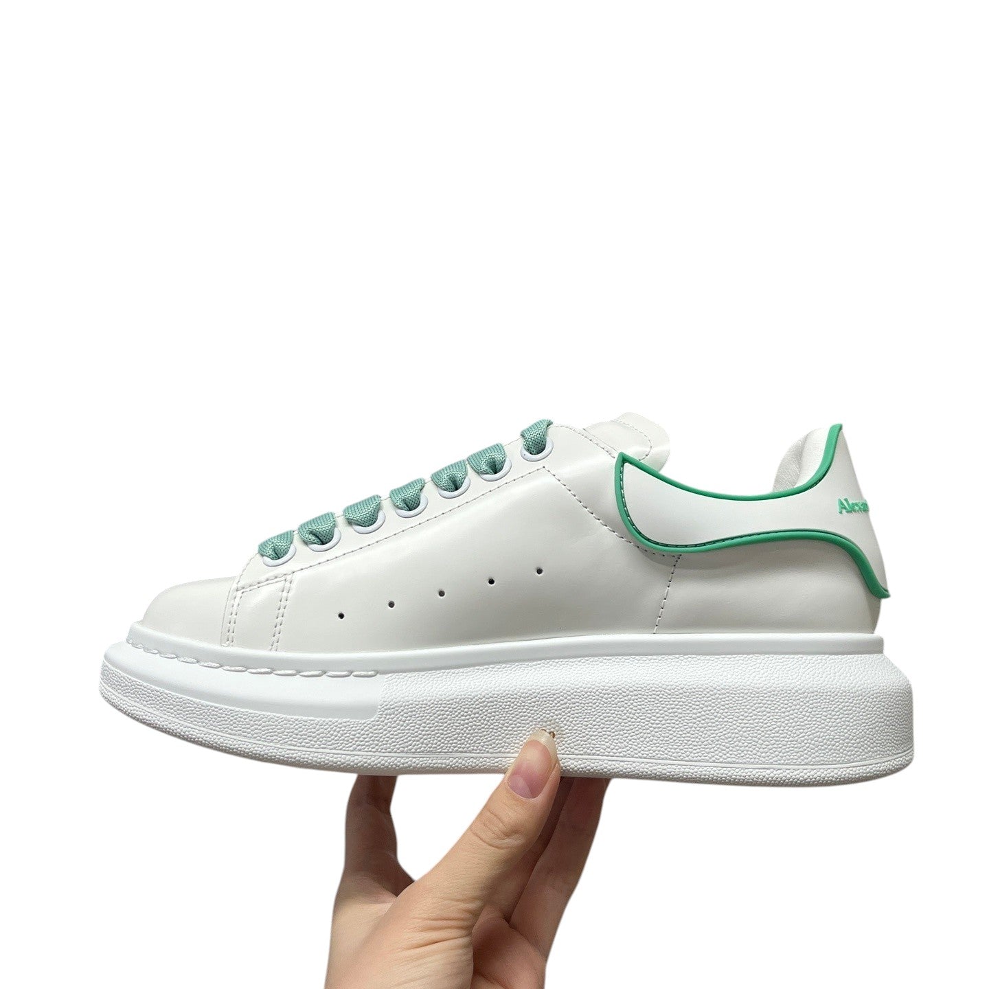Luxury Chef white leather sneakers with green trim and laces, featuring a chunky sole and Alexander McQueen branding.